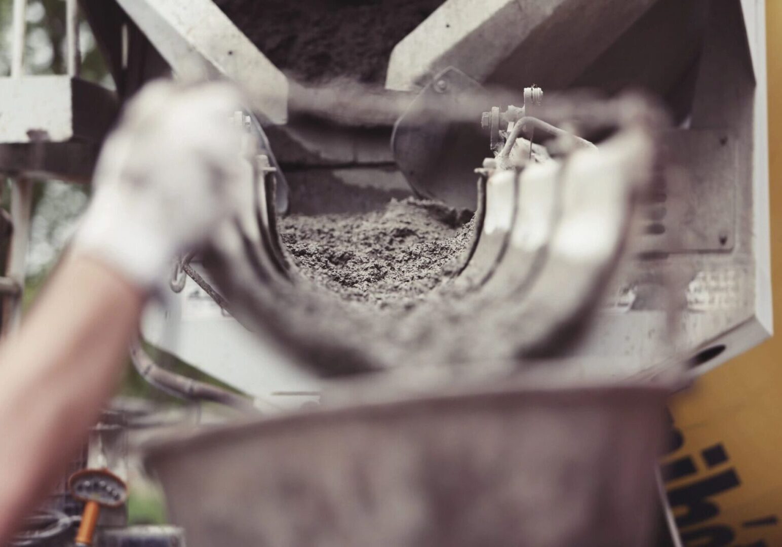 A person is pouring cement into a bucket.